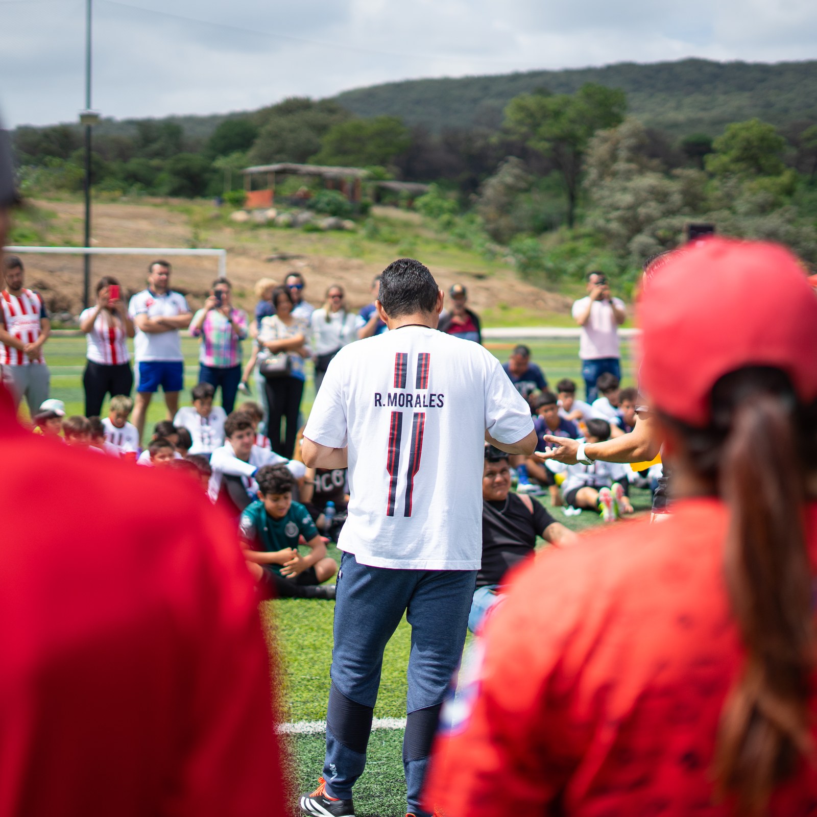 Ramón Morales, de espaldas con su camiseta RM11, reunido con niños y familias durante una clínica