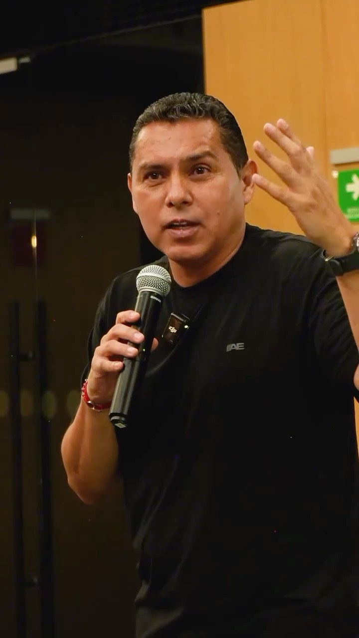 Ramón Morales en una conferencia, hablando al público con un micrófono
